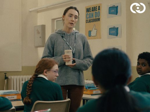 Saorise Ronan stars as a teacher. She is standing in a class of children.