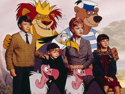 A young woman and three children are gathered with some animated characters includign a lion, a bear and a vulture.