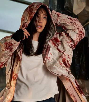 A young woman is running away from something. She is wearing a blood spattered hoodie.