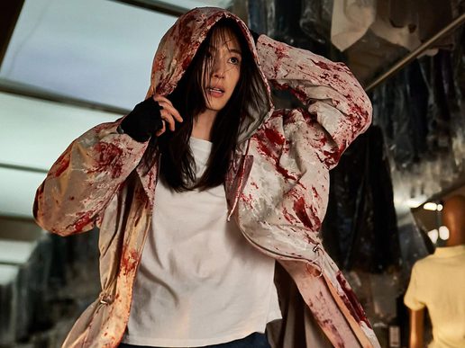A young woman is running away from something. She is wearing a blood spattered hoodie.