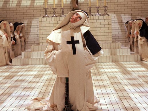 Vanessa Redgrave is in a stylised nuns outfit in a white panelled room.