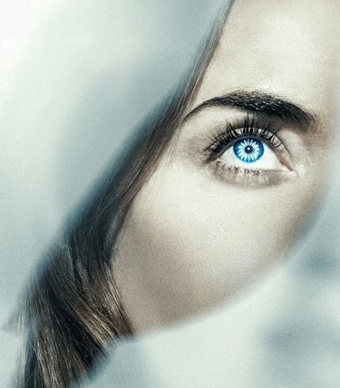 A close-up picture of Emily Blunt with a focus on her eye which is heavily coloured blue. There is a silhouette of a bird over her face.