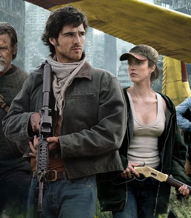 Cast includign jacob Elordi are standing in knee-high grass infront of a bi-plane.