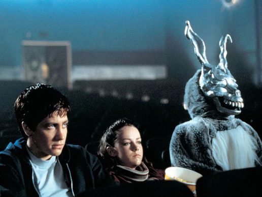 A young man and woman are sat in a cinema. They look sullen and are sat with a giant rabbit.