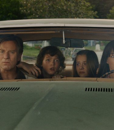 A family are sat in a car looking pensive.
