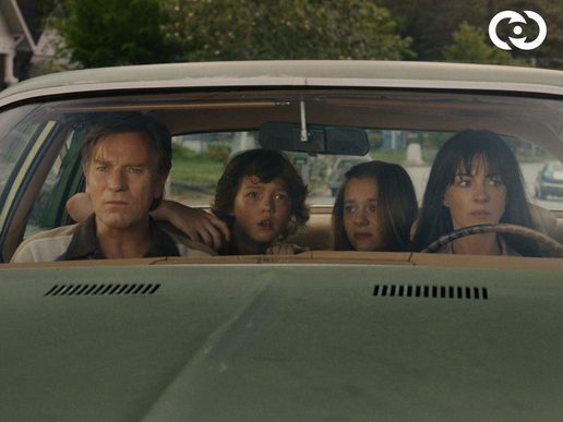 A family are sat in a car looking pensive.