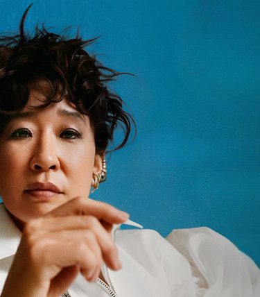 A close-up picture of Sandra Oh on a blue background.