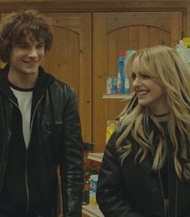 A young man and woman are in a grocery store. They look 90s rock and roll.