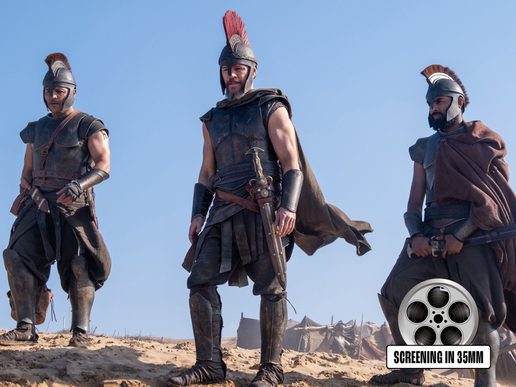 Three warriors in armour and helmets stand upon a cliff top.