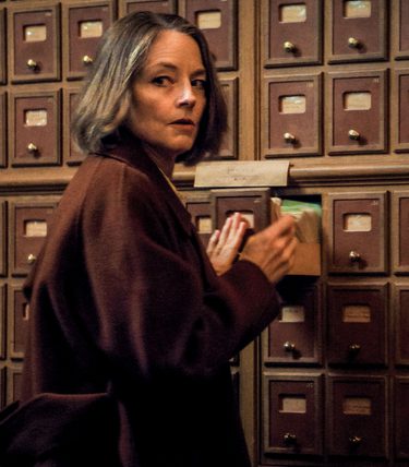 Jodie Foster is is looking in a record file, but looking around suspiciously.