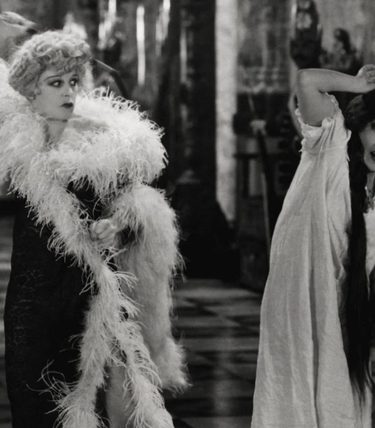 Black and white image of a well to do woman about to strike another woman.