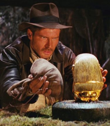 Indiana Jones is weighing up a bag of sand against a golden statue.