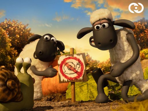 Shaun the Sheep and a sheep pal are showing a snail a 'No Snails' sign.