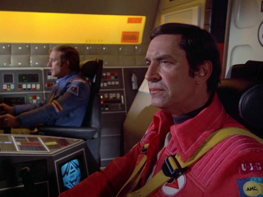 Martin Landau is sat in a spacehip looking toward the controls.