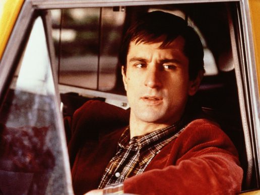 Robert De Niro is sat at the wheel of a taxi cab looking outwards.