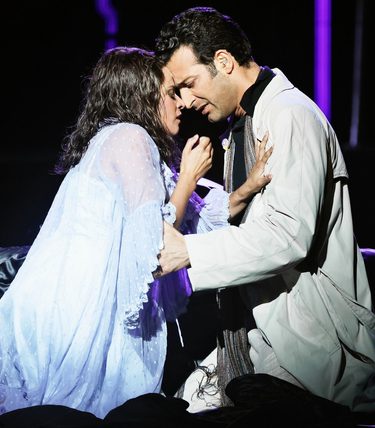 Two performers are crouched into an intimate embrace.