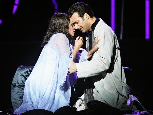 Two performers are crouched into an intimate embrace.