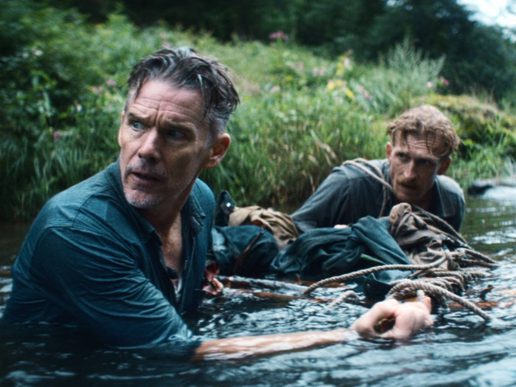 Ethan Hawke is chest high in a river, pulling something along with another man.