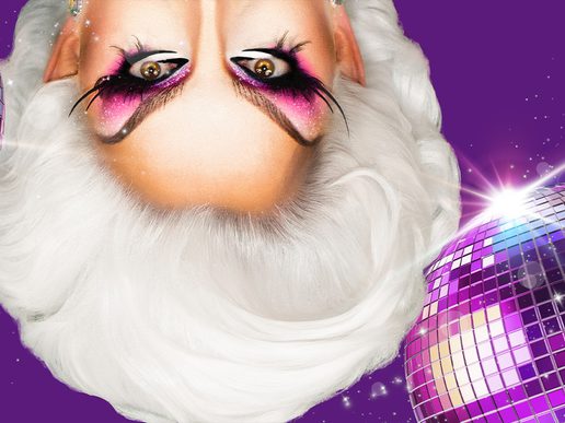 A close-up, upside-down image of a drag performer with dramatic white hair and bold pink-and-black eye makeup, framed against a bright purple background with a sparkling disco ball on the right side.
