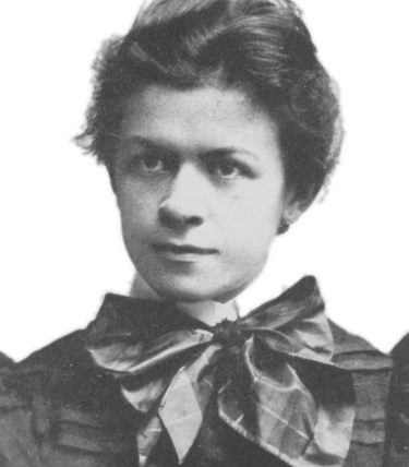 A black-and-white portrait of Mileva Marić, a Serbian physicist and mathematician known for her work in the early 20th century and her association with Albert Einstein. She is shown as a young woman with neatly styled hair, wearing a dark dress with puffed sleeves and a large, satin bow at the neck. Her expression is calm and serious, and she faces the camera directly against a plain white background, highlighting her features and period attire.